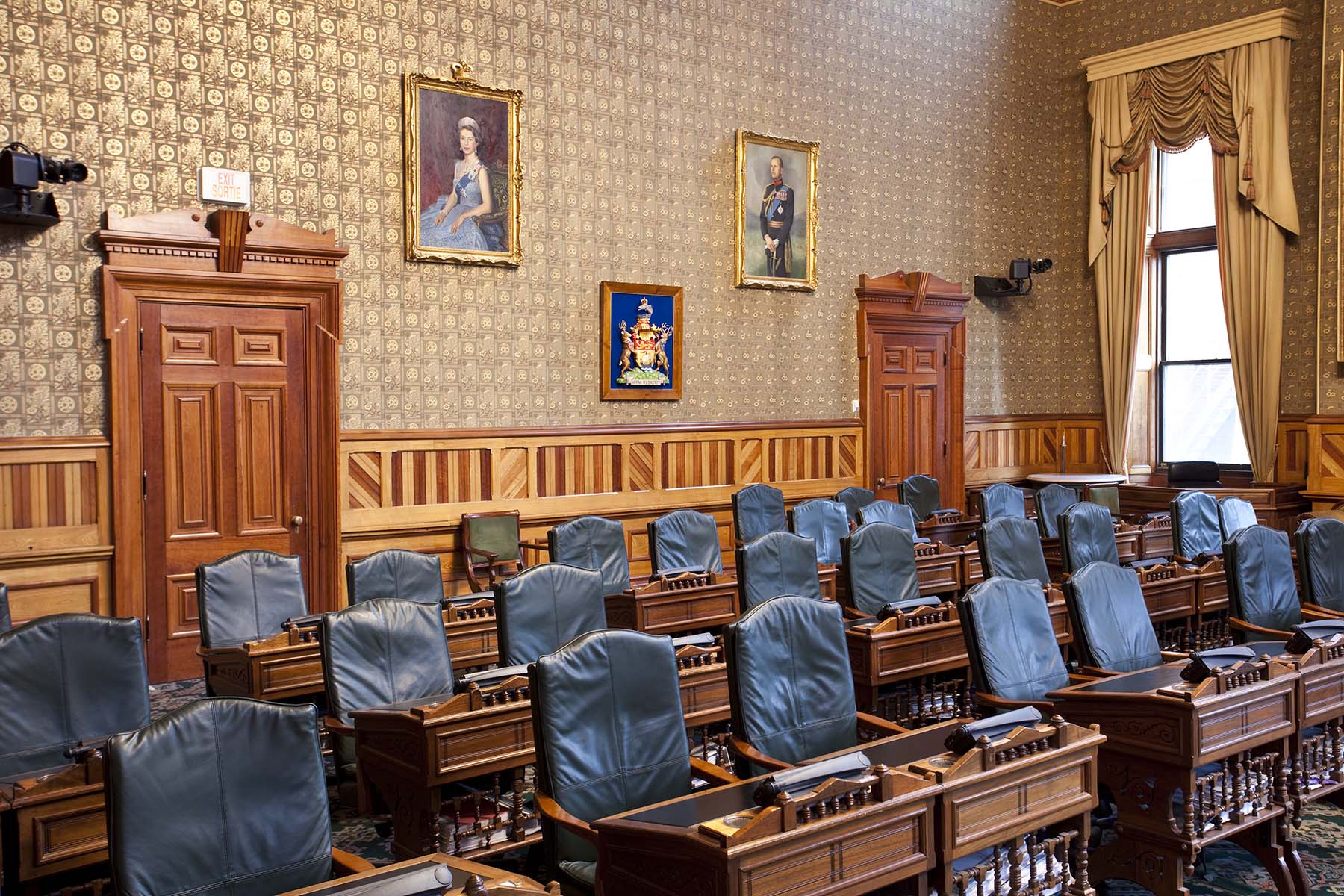 A photo of the legislative chamber, featuring several rows of empty chairs and desks for members.